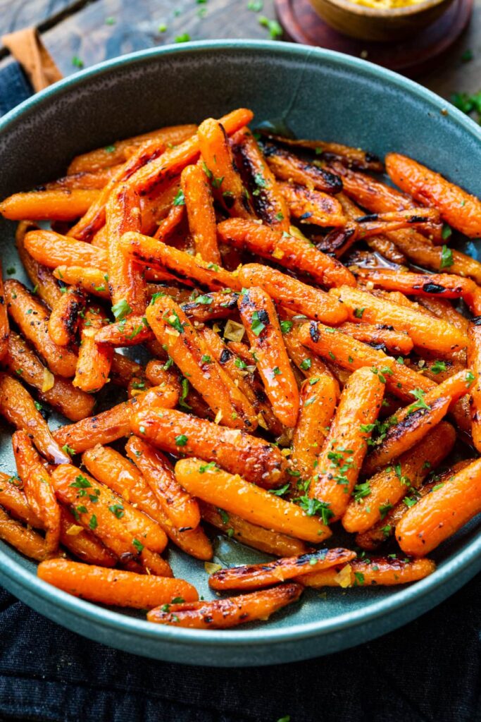 Roasted carrots glazed with honey butter in a large grey pot, garnished with parsley